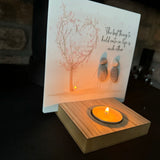 Perspex Quotable board 15cm & pebble image standing on a T-Light wooden block 
Two Pebble people standing together holding hands stood next to a pink blossom tree
Quote;
The best thing to hold onto in life is each other 