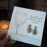 Perspex Quotable board 15cm & pebble image standing on a T-Light wooden block 
Two Pebble people standing together holding hands stood next to a pink blossom tree
Quote;
The best thing to hold onto in life is each other 