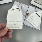 Radar Poetry - White Porcelain Glazed House shape 12x7cm hanging decoration  
Quote in a soft gold text - 'Happiness is homemade' with a leather thong detail