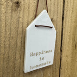 Radar Poetry - White Porcelain Glazed House shape 12x7cm hanging decoration  
Quote in a soft gold text - 'Happiness is homemade' with a leather thong detail
