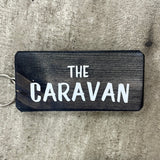Wooden block keyring with white text quote on both sides; 'The Caravan'  black
