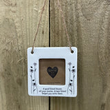 Beautiful white ceramic photo frame with floral detailing up the sides. In the middle is space for a small photo with quote "A good friend knows all your stories. A best friend helped you write them." written underneath. Hung with a jute rope.