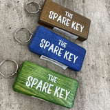 Made in the UK by Giggle Gift Co. Wooden block keyring with white text quote on both sides; 'The Spare Key'