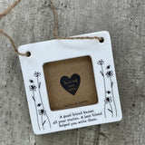 Beautiful white ceramic photo frame with floral detailing up the sides. In the middle is space for a small photo with quote "A good friend knows all your stories. A best friend helped you write them." written underneath. Hung with a jute rope.