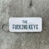 Made in the UK by Giggle Gift Co. Wooden block keyring with white text quote on both sides; 'The Fucking Keys' white