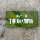 Made in the UK by Giggle Gift Co. Wooden block keyring with white text quote on both sides; 'Key to the Unknown'  green