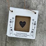 Beautiful white ceramic photo frame with floral detailing up the sides. In the middle is space for a small photo with quote "A good friend knows all your stories. A best friend helped you write them." written underneath. Hung with a jute rope. 