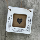Beautiful white ceramic photo frame with floral detailing up the sides. In the middle is space for a small photo with quote "A good friend knows all your stories. A best friend helped you write them." written underneath. Hung with a jute rope.