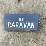 Wooden block keyring with white text quote on both sides; 'The Caravan'  grey