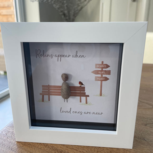 Mini Framed Pebble Art -White block square frame 12.5cmThis frame has the image of directional sign saying 'always in my heart' and a bench with a pebble person sitting on it with a robin and the quote 'Robins appear when loved ones are near' 