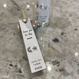 Sweet asymmetrical stud earrings - one shaped like a star and the other a moon - presented in a message bottle on a card that reads "love you to the moon"  Sterling Silver