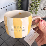 Belly Button Designs - Mabel Range
Stoneware Mug 340ml hand-painted wide, yellow &amp; white vertical stripes
Text stamped on the front - Human Sunshine