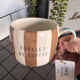 Belly Button Designs - Mabel Range
Stoneware Mug 340ml hand-painted wide, earthy brown &amp; white vertical stripes
Text stamped on the front - Fuelled by Coffee
