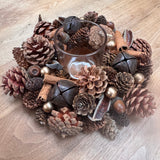 Round t-light centrepiece with layers of pinecones, cinnamon sticks, foliage in rich warm colours 24cm