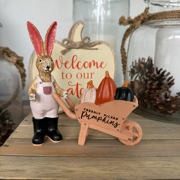 Standing Ruth Rabbit with wellies & dungarees pushing a wheelbarrow filled with freshly picked Pumpkins