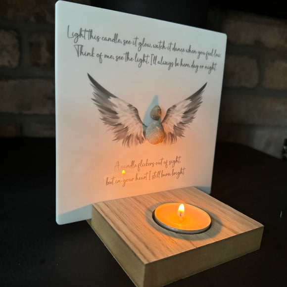 Perspex Quotable board 15cm & pebble image standing on a T-Light wooden block 

Pebble person with open beautiful angel wings in grey & white shades

Quote;

Light this candle, see it glow, watch it dance when you feel low.

Think of me, see the light.  I'll always be here, day or night.

A candle flickers out of sight. 

but in your heart I still burn bright.