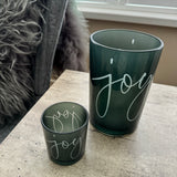 Round Glass Hurricane Vase in a Deep Green/Grey colour
Has the word 'Joy' in a scrolling text on both sides
Available in 2 sizes; Small H8cm &amp; Large H18cm&nbsp;