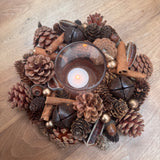 Round t-light centrepiece with layers of pinecones, cinnamon sticks, foliage in rich warm colours 24cm
