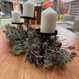 Triple candle holder Needle Pinecone Table Centre L60cm&nbsp;

Tiered black metal frame with three flat pillar candle plates, nestled inside a bed of realistic artificial frosted long-needle pine branches and real pinecones.