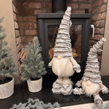 Standing Gonk with extendable legs & Sitting Gonk wearing a tall ribbed faux fur grey hat, button nose and a fluffy white beard with gold threads giving it a little sparkle 