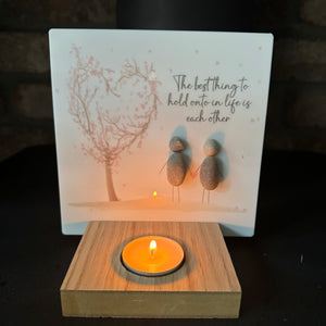 Perspex Quotable board 15cm &amp; pebble image standing on a T-Light wooden block&nbsp;

Two Pebble people standing together holding hands stood next to a pink blossom tree

Quote;

The best thing to hold onto in life is each other&nbsp;