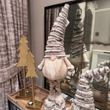 Standing Gonk with extendable legs wearing a tall ribbed faux fur grey hat, button nose and a fluffy white beard with gold threads giving it a little sparkle H70-100cm&nbsp;