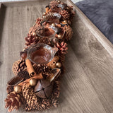 Table centrepiece with pinecones, cinnamon sticks, foliage in rich warm colours and 4 t-light cups integrated 51cm