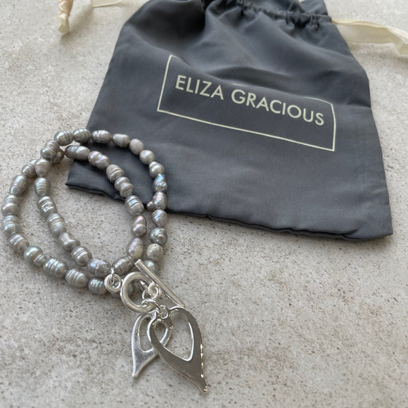 Eliza Gracious quality - affordable design led branded costume jewellery.  Light Grey seed shape Freshwater Pearl Bracelet with twin hearts charm EB0543