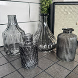 New Cool Grey Small Glass Bottle Vases
Various styles to mix &amp; match and all sold individually;
Diamond Shaped Small Vase H15 x W8cm&nbsp; - £5.00

Ribbed Wide Base Bud Vase H15 x W12cm&nbsp; - £5.00
Mini Geometric Bottle H9cm x Dia 5cm - £2.00
Small Dimpled H10 x 5cm - £2.00