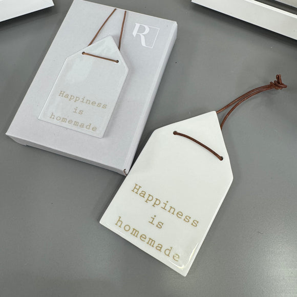 Radar Poetry - White Porcelain Glazed House shape 12x7cm hanging decoration  
Quote in a soft gold text - 'Happiness is homemade' with a leather thong detail