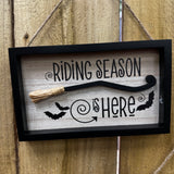 Halloween Broomstick hanging sign 21x14cm a black and wood framed with 3D miniature broomstick &amp; textured straw brush tied to the end
Quote - 'Riding Season is Here' with images of bats flying&nbsp;