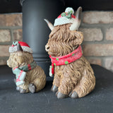 Christmas Highland Cow wearing a hat with holly seasonal scarf with a little sparkle
Available in 2 sizes - Small H10.5cm &amp; Large H17cm