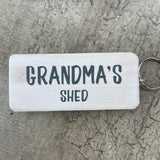 Made in the UK by Giggle Gift Co. Wooden block keyring with white text quote on both sides; 'Grandma's Shed'  white