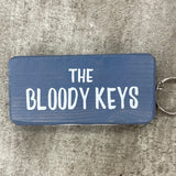 Made in the UK by Giggle Gift Co. Wooden block keyring with white text quote on both sides; 'The Bloody Keys'  Grey