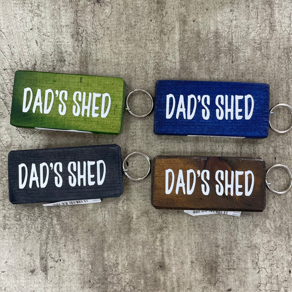 Made in the UK by Giggle Gift Co. Wooden block keyring with white text quote on both sides; 'Dad's Shed' 