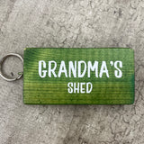 Made in the UK by Giggle Gift Co. Wooden block keyring with white text quote on both sides; 'Grandma's Shed'  green