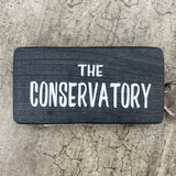 Wooden block keyring with white text quote on both sides; 'The Conservatory'  Black