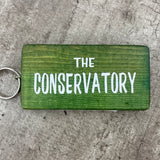 Wooden block keyring with white text quote on both sides; 'The Conservatory'  Green