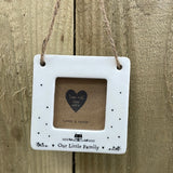 Beautiful white ceramic photo frame with heart detailing up the sides and a cute house illustration. In the middle is space for a small photo with quote "Our Little Family" written underneath. Hung with a jute rope.