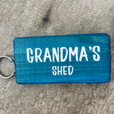 Made in the UK by Giggle Gift Co. Wooden block keyring with white text quote on both sides; 'Grandma's Shed'  blue