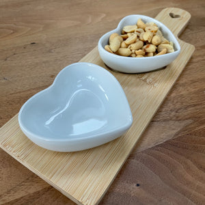 Ceramic heart shaped dishes sat in grooves on a wooden serving board. They look so stylish and great when hosting a gathering at your home to place olives, nuts etc inside. Available in two sizes - 2 or 3 heart dishes