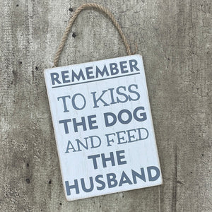 Metal sign reading "Remember to kiss the dog and feed the husband"