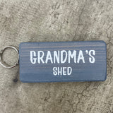 Made in the UK by Giggle Gift Co. Wooden block keyring with white text quote on both sides; 'Grandma's Shed'  grey