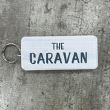 Wooden block keyring with white text quote on both sides; 'The Caravan'  white