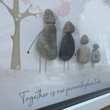 Framed Pebble Art - White block frame 31.5cmWith a soft background image of a Tree with the leaves being pink hearts blowing in the wind and 4 pebble people - 2 adults & 2 children holding hands with the quote 'Our Perfect Little Family... Together is our favourite place to be'