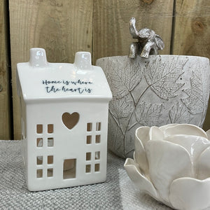 White Ceramic T Light House with battery T-Light included reading the quote: "Home is where the heart is"