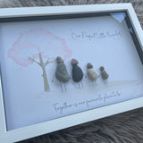 Framed Pebble Art - White block frame 31.5cmWith a soft background image of a Tree with the leaves being pink hearts blowing in the wind and 4 pebble people - 2 adults & 2 children holding hands with the quote 'Our Perfect Little Family... Together is our favourite place to be'