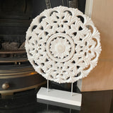 Beautiful carved wooden circle panel with a distressed white finish on iron legs and a wooden base.