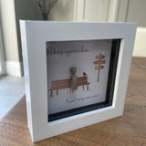 Mini Framed Pebble Art -White block square frame 12.5cmThis frame has the image of directional sign saying 'always in my heart' and a bench with a pebble person sitting on it with a robin and the quote 'Robins appear when loved ones are near'