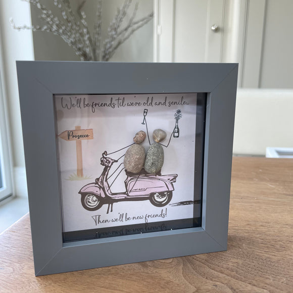 Mini Framed Pebble Art - Grey block square frame 12.5cmThe background is fun with a pink scooter with two pebble friends sitting on it toasting with prosecco with the quote 'We'll be friends til we're old and senile...Then we'll be new friends!' 